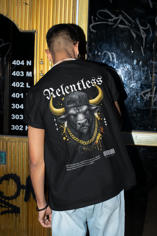 Person wearing a black t-shirt with a graphic design of a bull and "Relentless" text, standing in front of a wall with numbers and graffiti.
