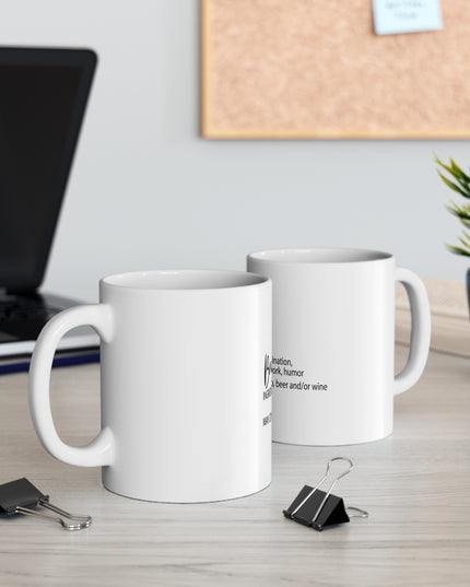 Two white mugs on a desk with a laptop and plant in the background