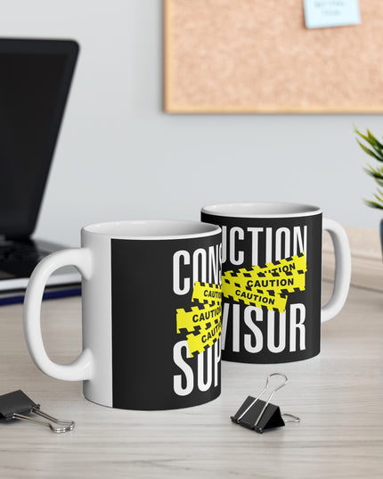 Two black mugs with 'CONSTRUCTION SUPERVISOR' text on a desk with office supplies.