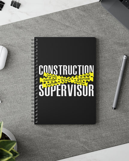 Notebook with 'Construction Supervisor' text on a desk with a pen and earbuds.