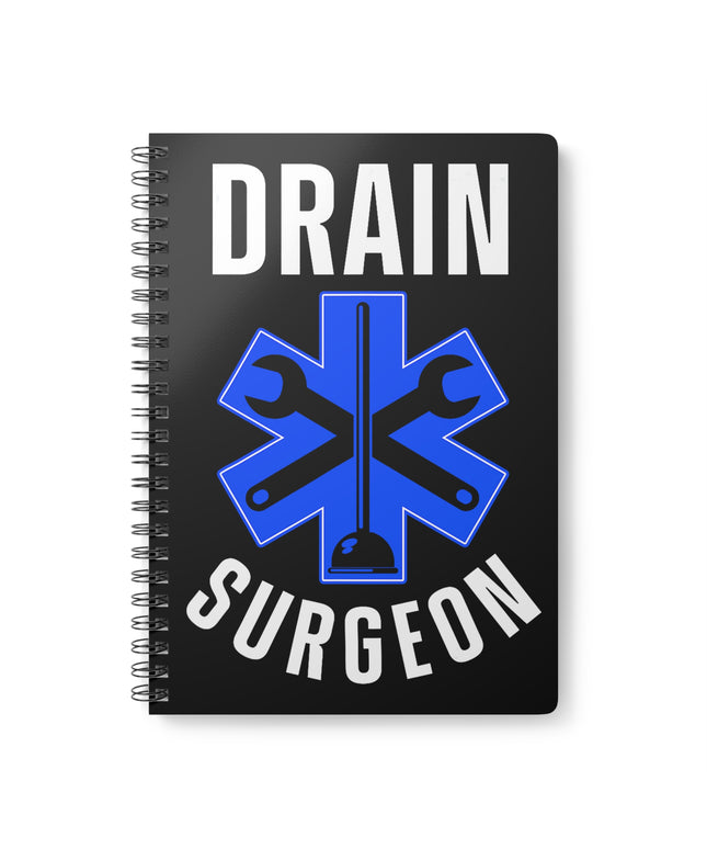 Black spiral A5 plumber notebook with "Drain Surgeon" text and a blue medical cross graphic that include plumbing tools, on a white background