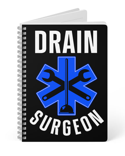 Black partially opened spiral A5 plumber notebook with "Drain Surgeon" text and a blue medical cross graphic that include plumbing tools, on a white background