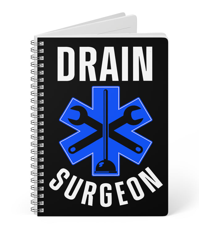 Black partially opened spiral A5 plumber notebook with "Drain Surgeon" text and a blue medical cross graphic that include plumbing tools, on a white background