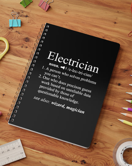 Notebook with electrician definition on a wooden surface with stationery items