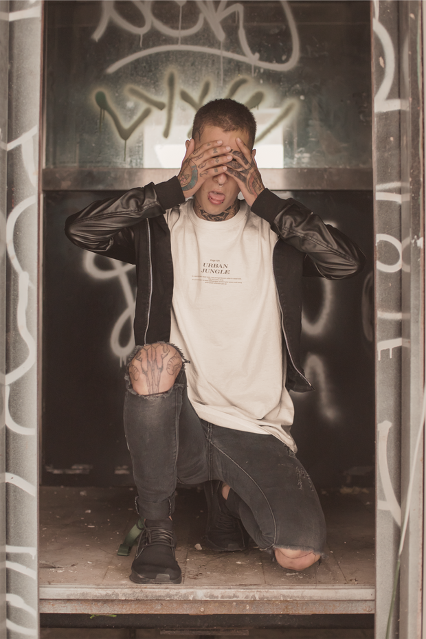 Person sitting on a ledge with hands over face in an urban setting with graffiti.