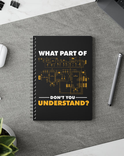 Black spiral notebook with "What part of don't you understand?" graphic, on a white table